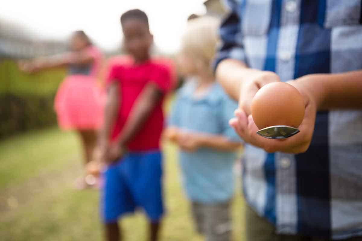 Close up of a child holding an egg on a spoon which is a popular picnic game.