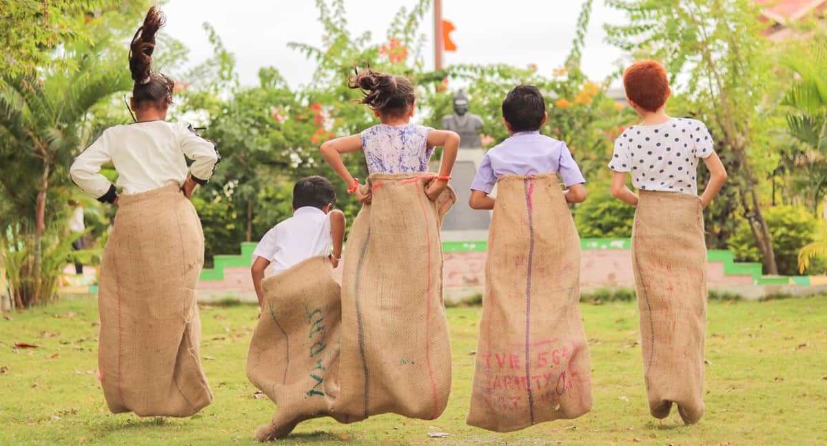 A line of kids jumping in potato sacks in a race. 
