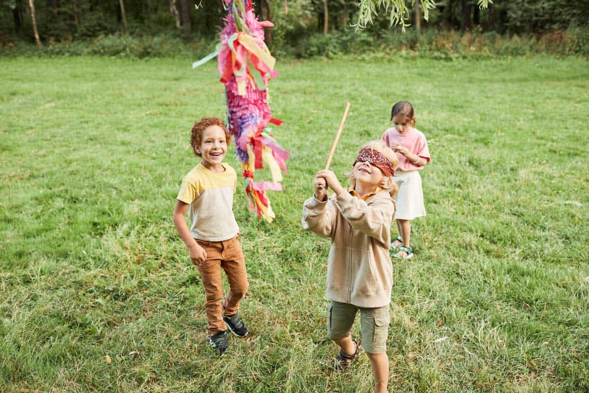 Children playing with a piñata at a birthday in the park. 