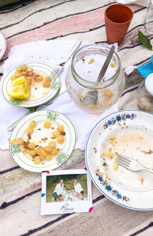 Empty plates on a picnic blanket with a polaroid photo of a couple. 