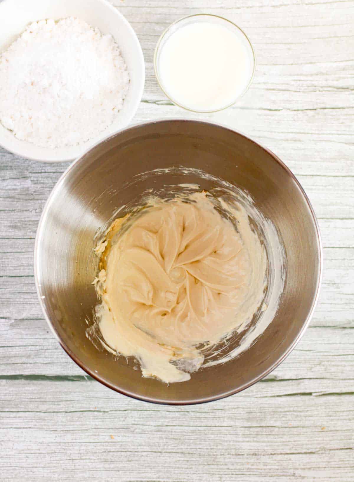 A metal bowl with flour, sugar and butter on a wooden table.