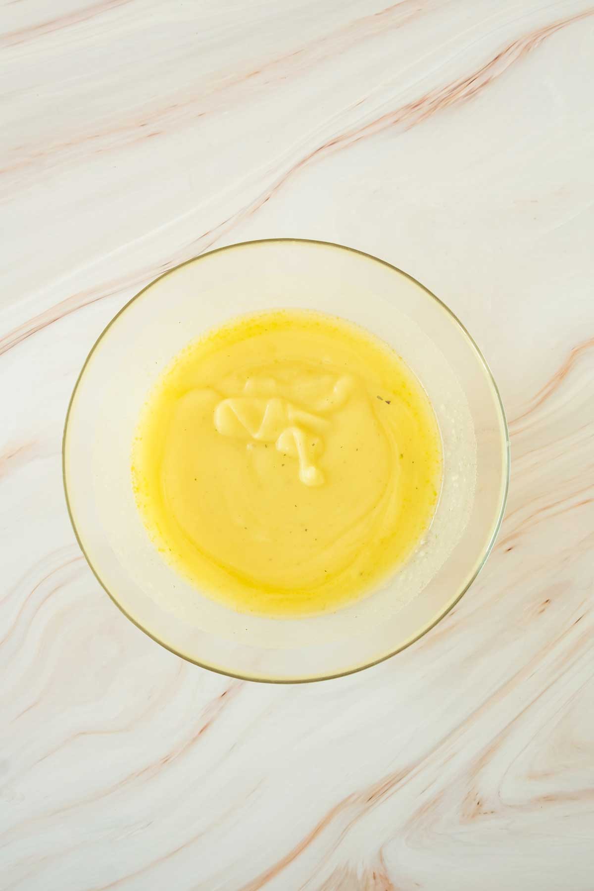 A bowl of yellow soup on a marble table.