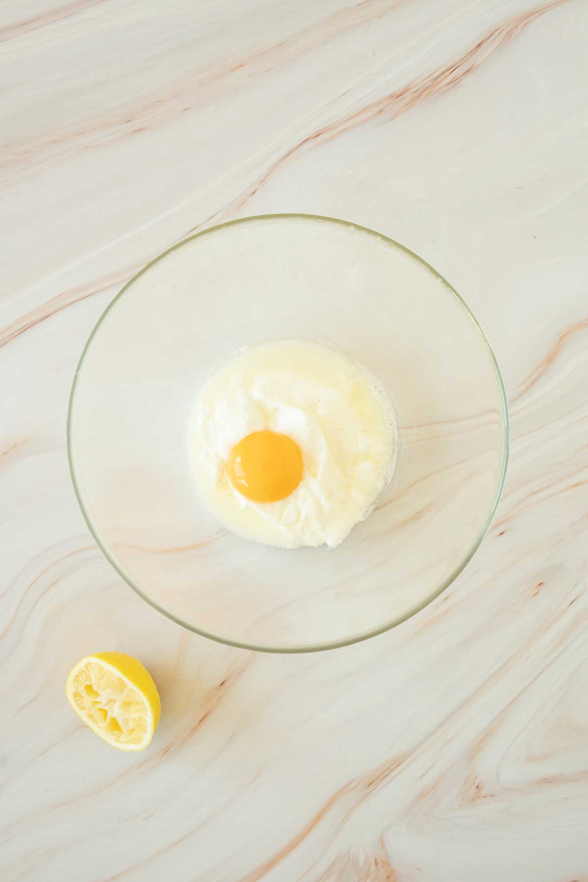 An egg in a glass bowl on a marble surface.