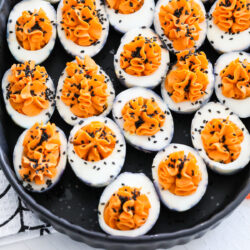 Halloween deviled eggs in a black pan.