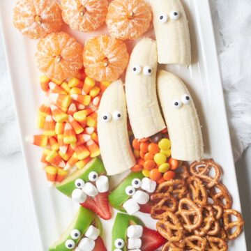 A plate of halloween snacks with candy and pretzels.