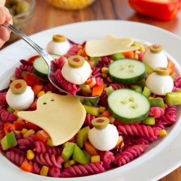 A plate of pasta salad with carrots, cucumbers and tomatoes.