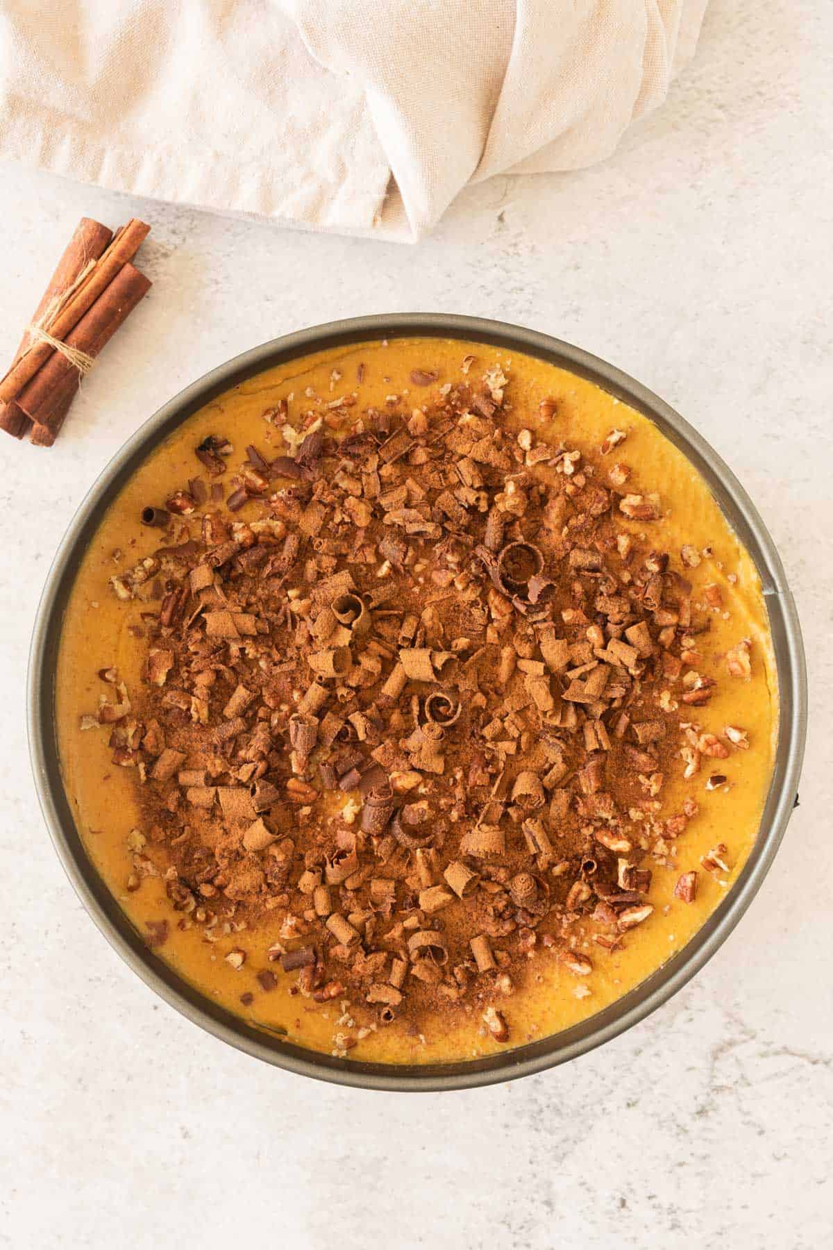 A pumpkin pie in a pan with cinnamon and nuts.
