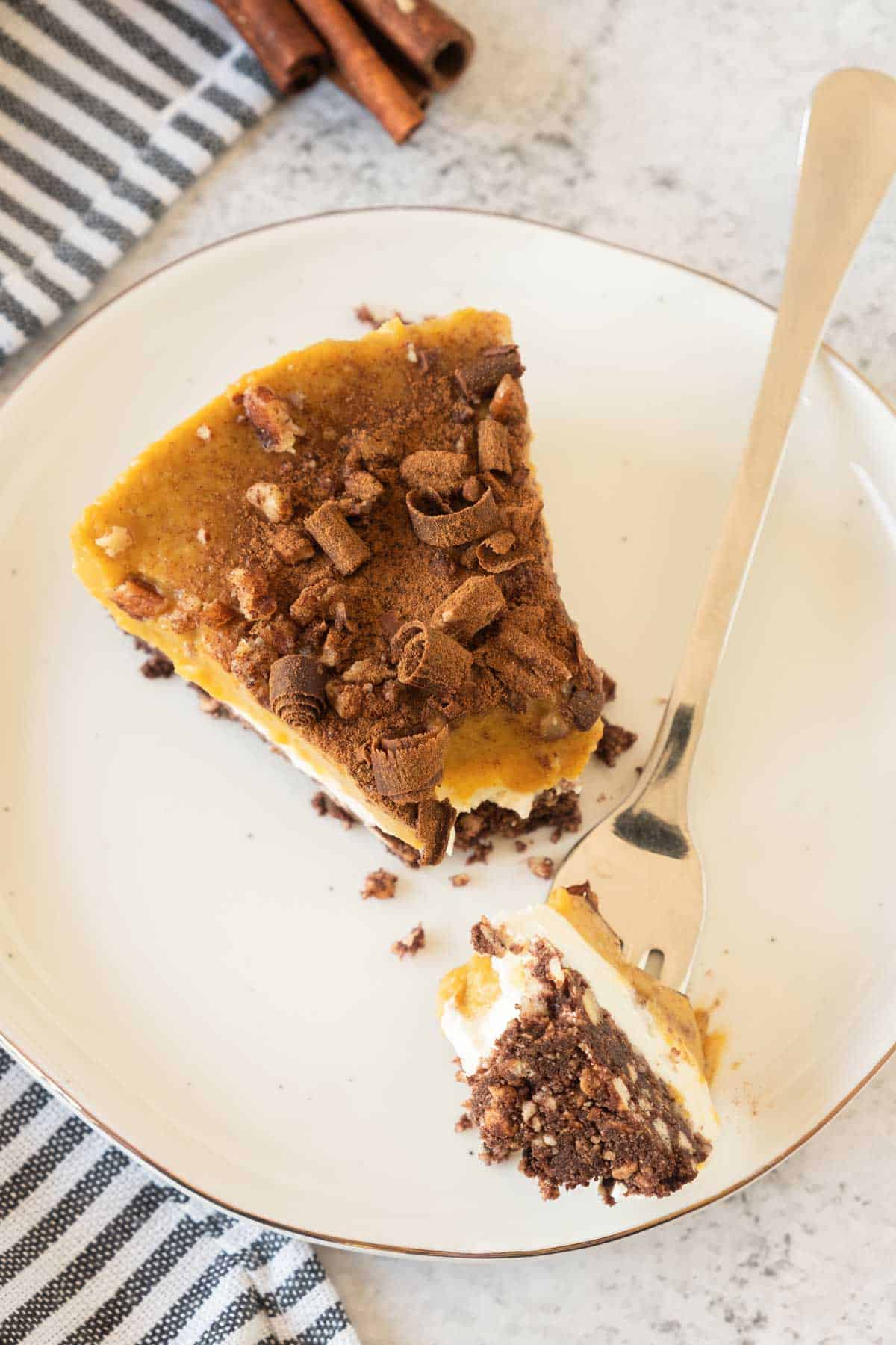 A slice of pumpkin pie on a plate with a fork.