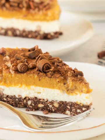 A slice of pumpkin cheesecake on a plate with a fork.