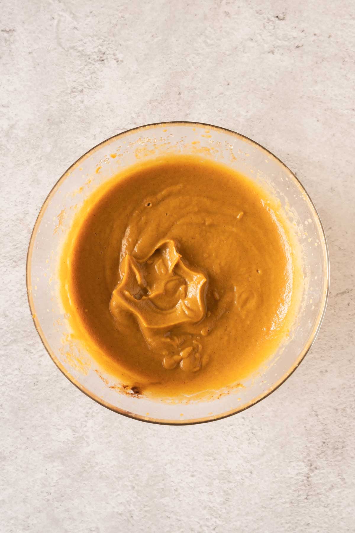 A bowl of pumpkin puree on a white surface.