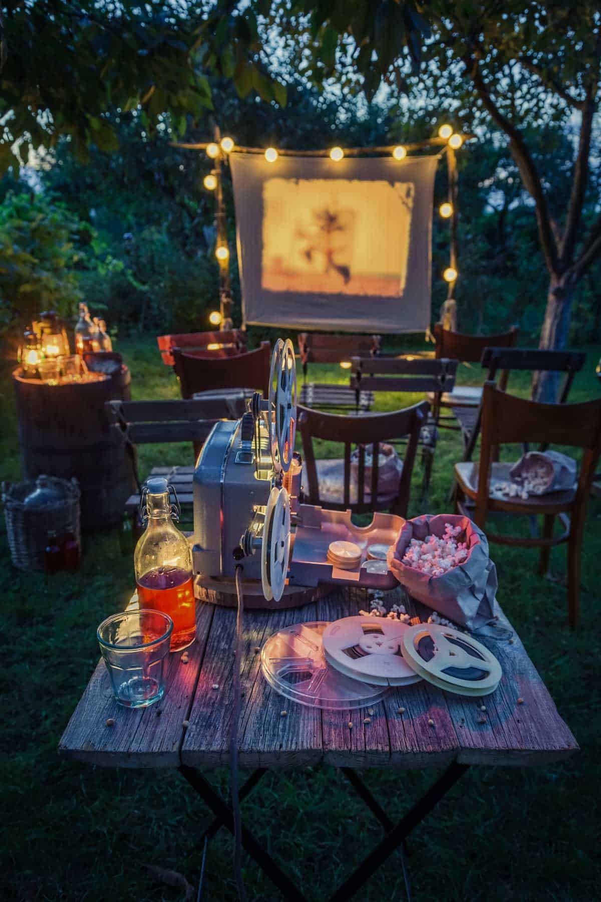 A table with a movie projector set up in a backyard.