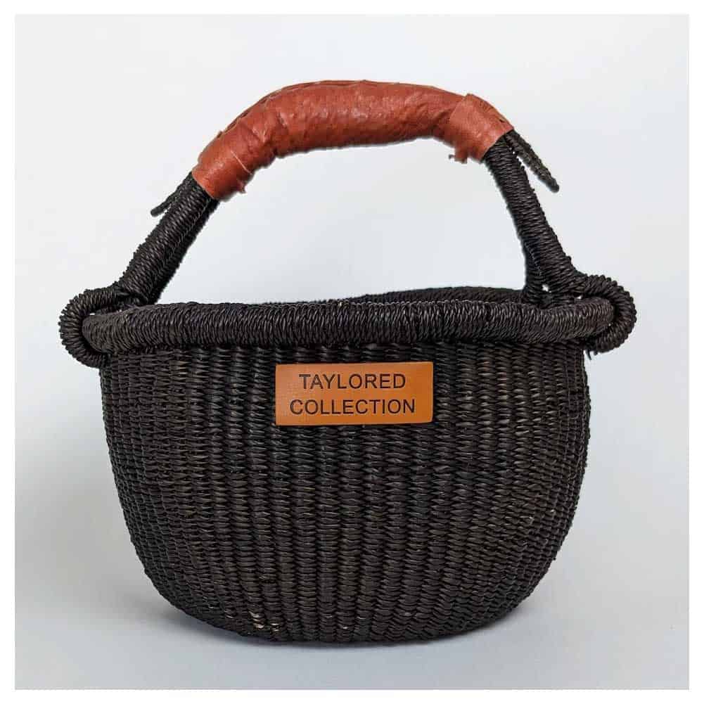 A black woven basket with a leather handle.