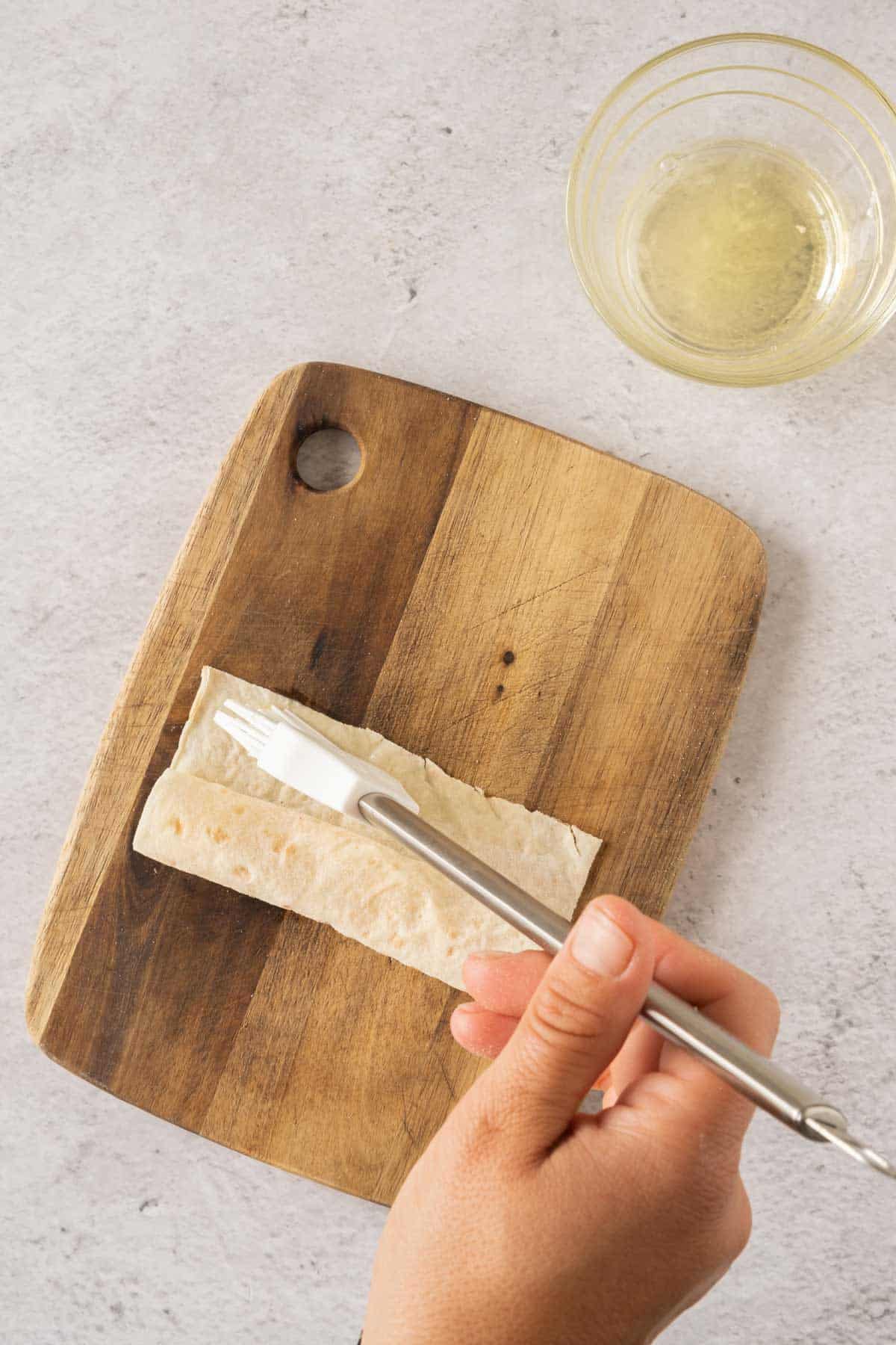 A person brushing filo pastry on a cutting board.