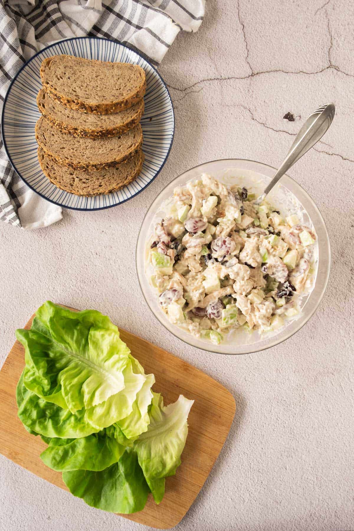 A bowl of chicken salad and bread on a table.