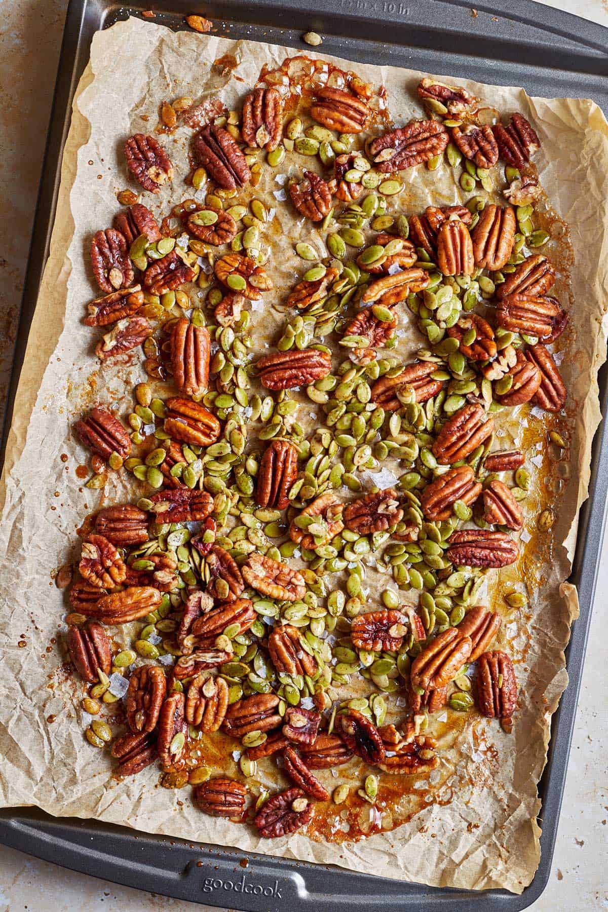 Roasted pecans and pumpkin seeds on a baking sheet.