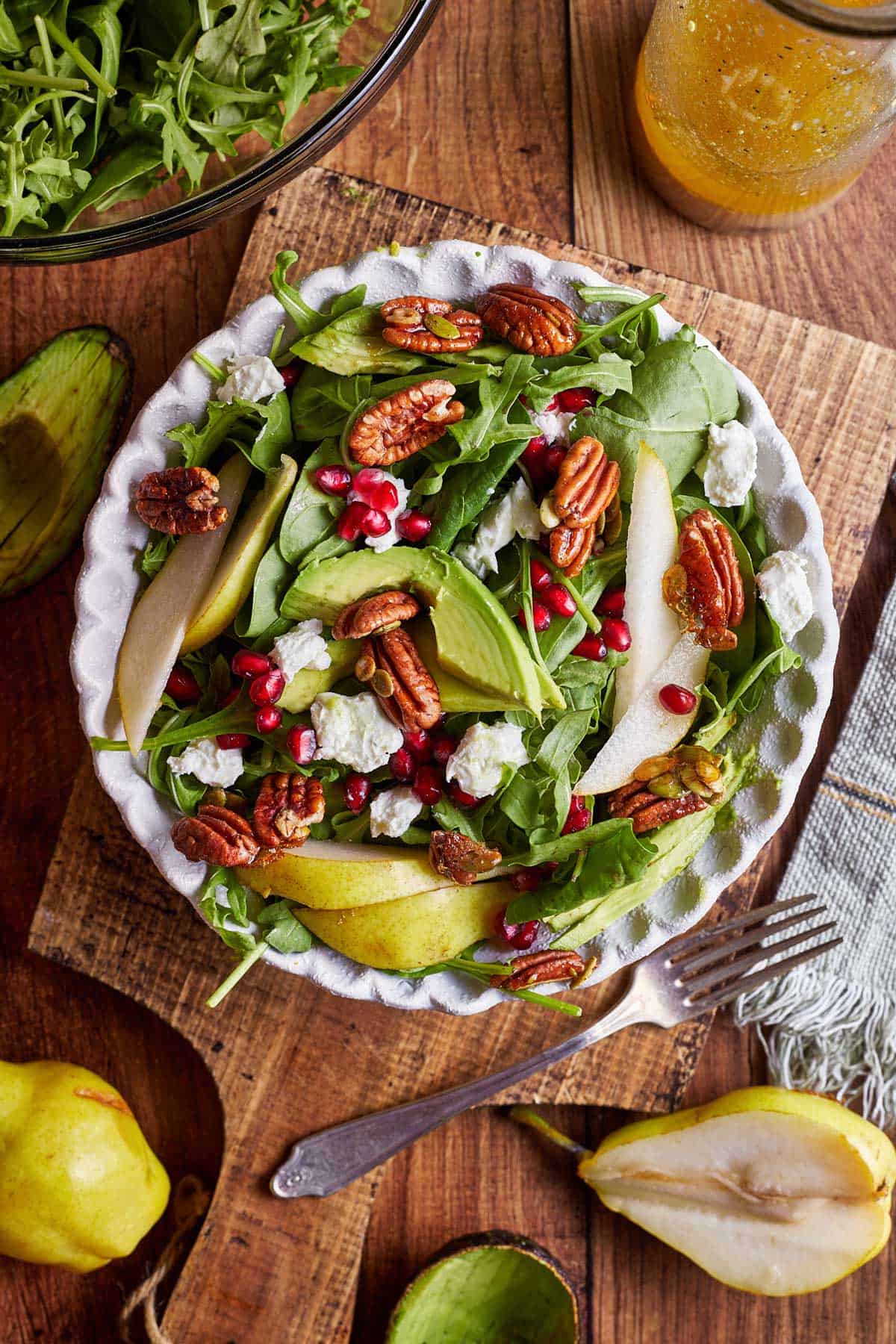 A salad with pears, goats cheese, pecans and pomegranate.