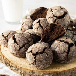Chocolate Snowball cookies on a wooden board with a glass of milk.