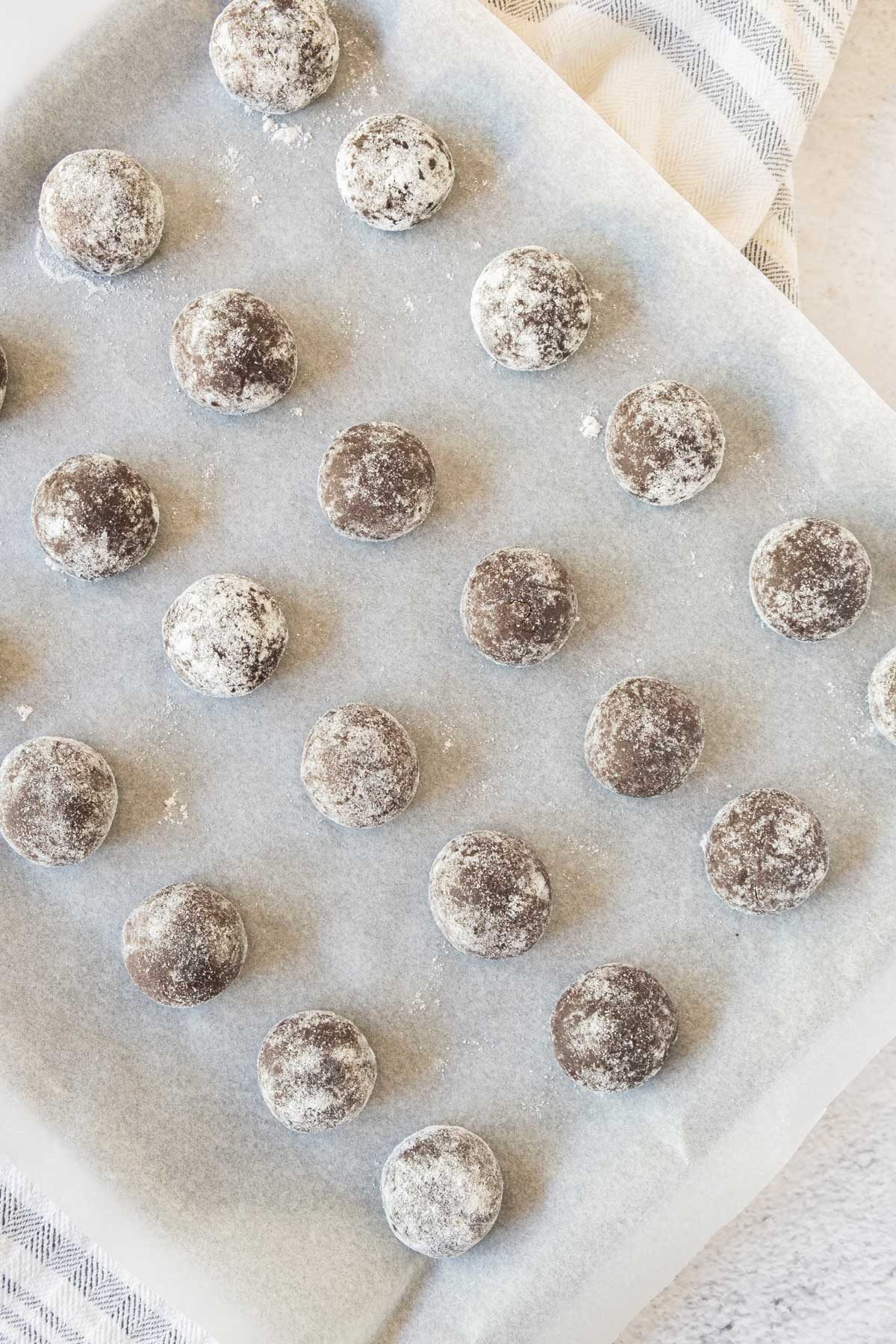Chocolate snowball cookies on a baking sheet.