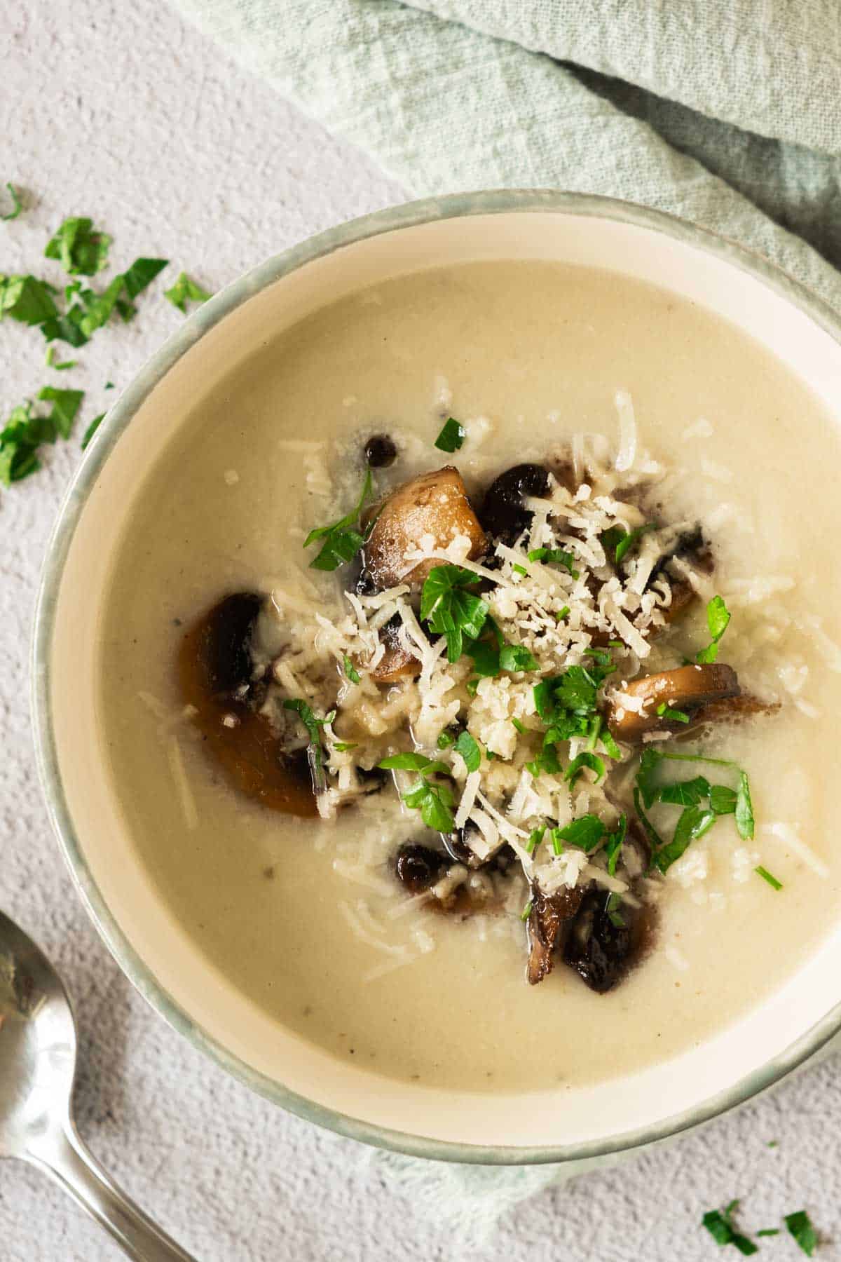 A bowl of soup with mushrooms and parmesan.