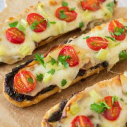 Cheese and olive bread with melted cheese and tomatoes on it.