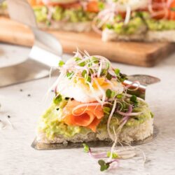 Avocado with smoked salmon and sprouts on a heart shaped sandwich.