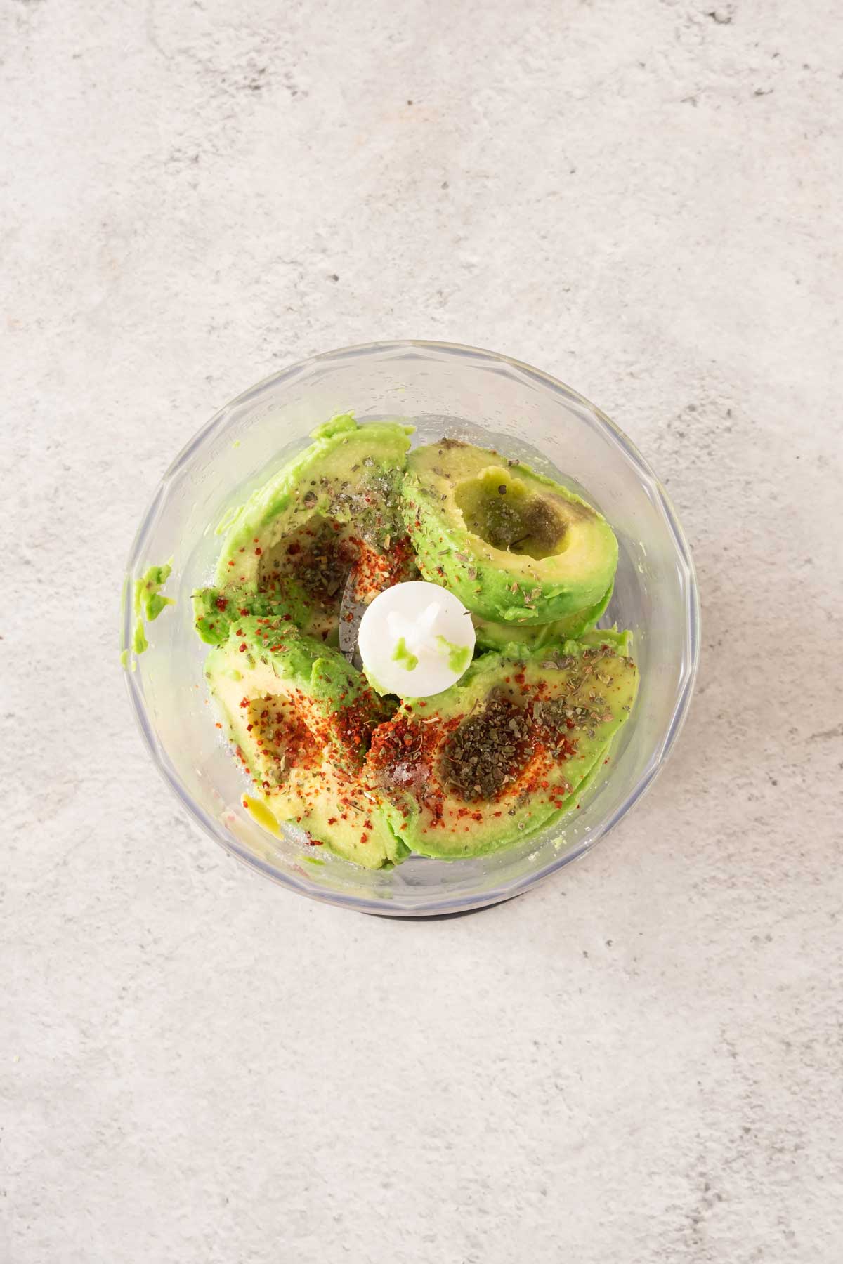 Avocado in a food processor with spices.