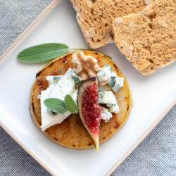 A pear, fig and blue cheese appetizer on a plate with crackers.