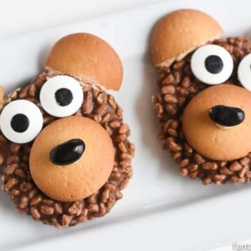 Two bear cookies on a plate with eyes on them.