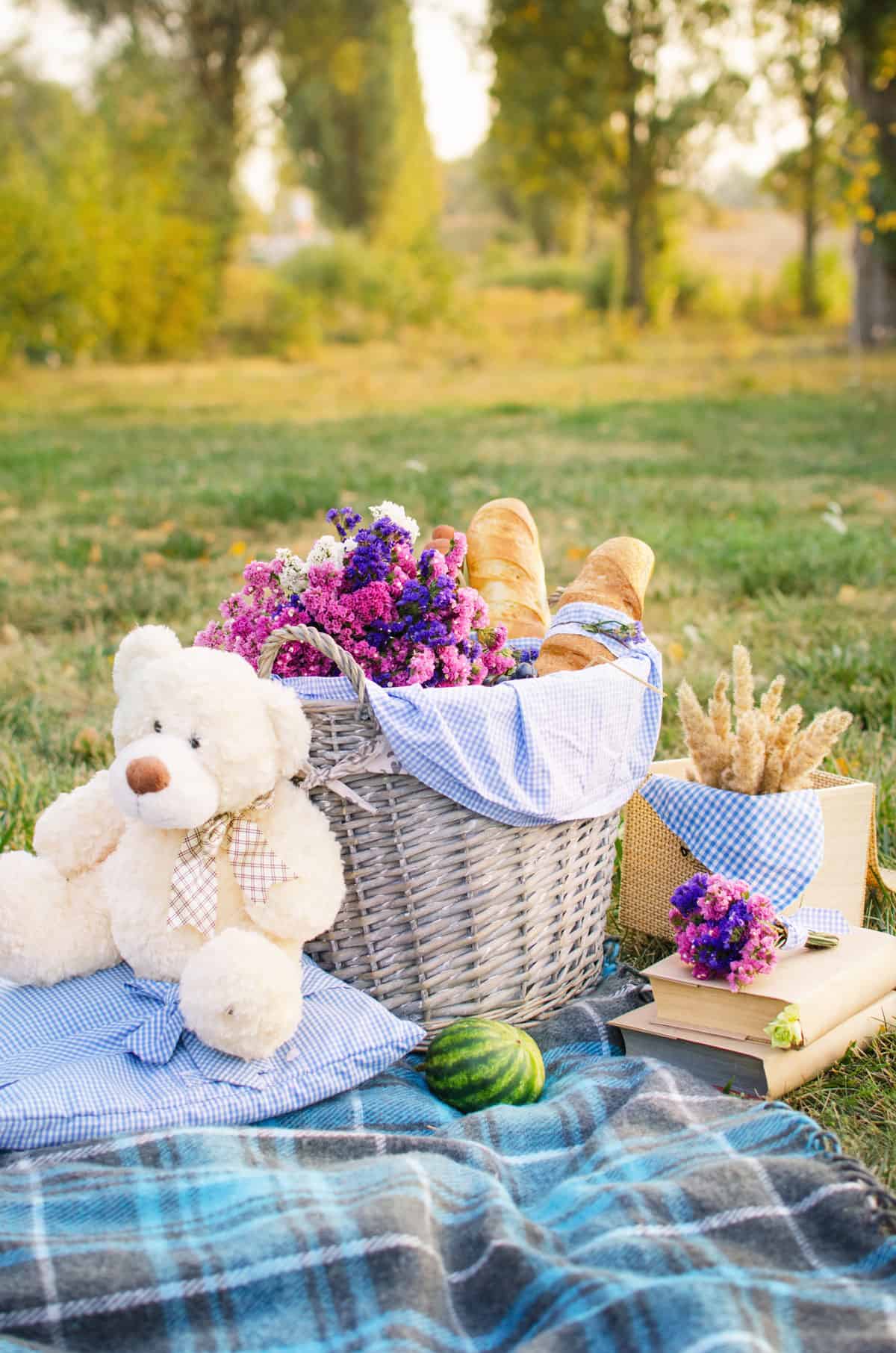 Picnic basket with flowers, bread and a teddy bear.