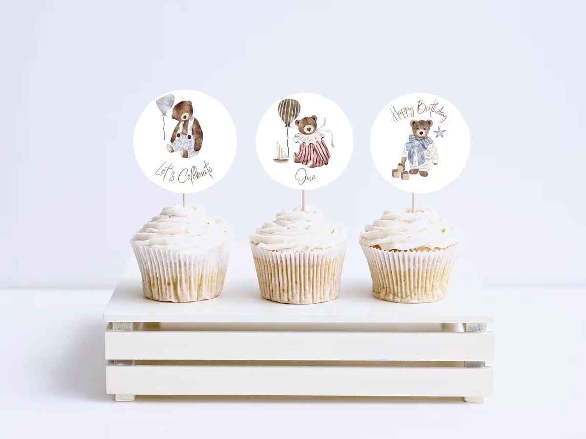 Three cupcakes with teddy bear cake toppers on them.
