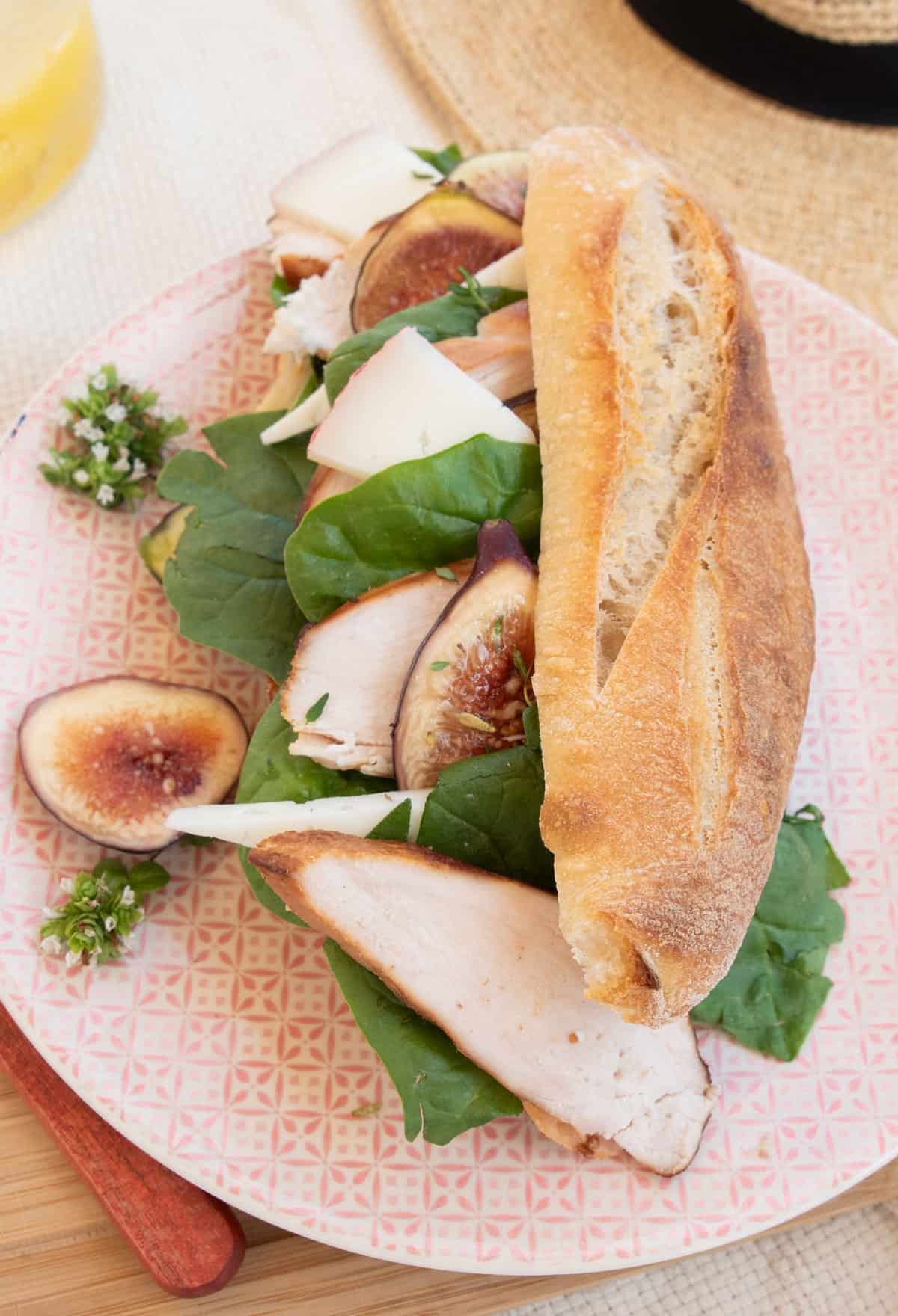 Fig and chicken baguette on a pink plate.