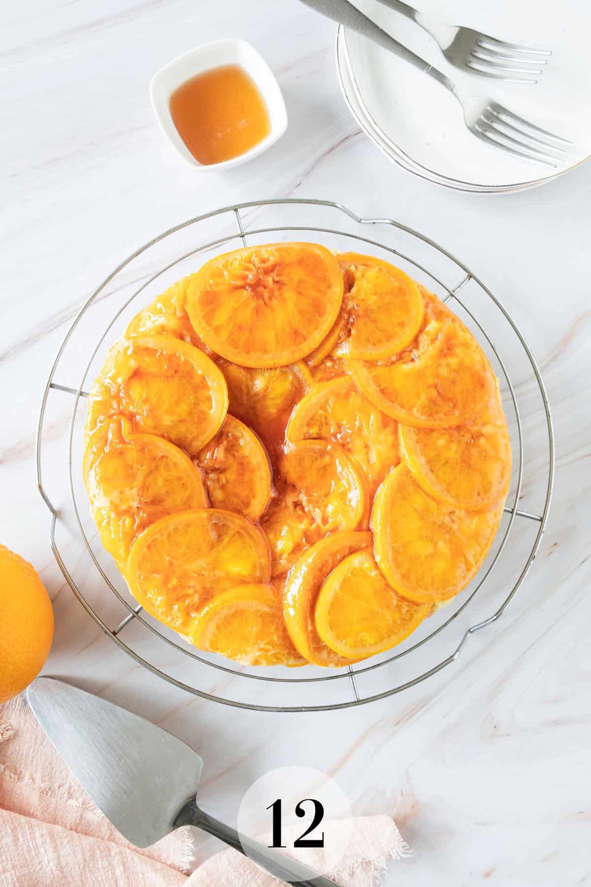 An orange cake on a plate with a fork next to it.