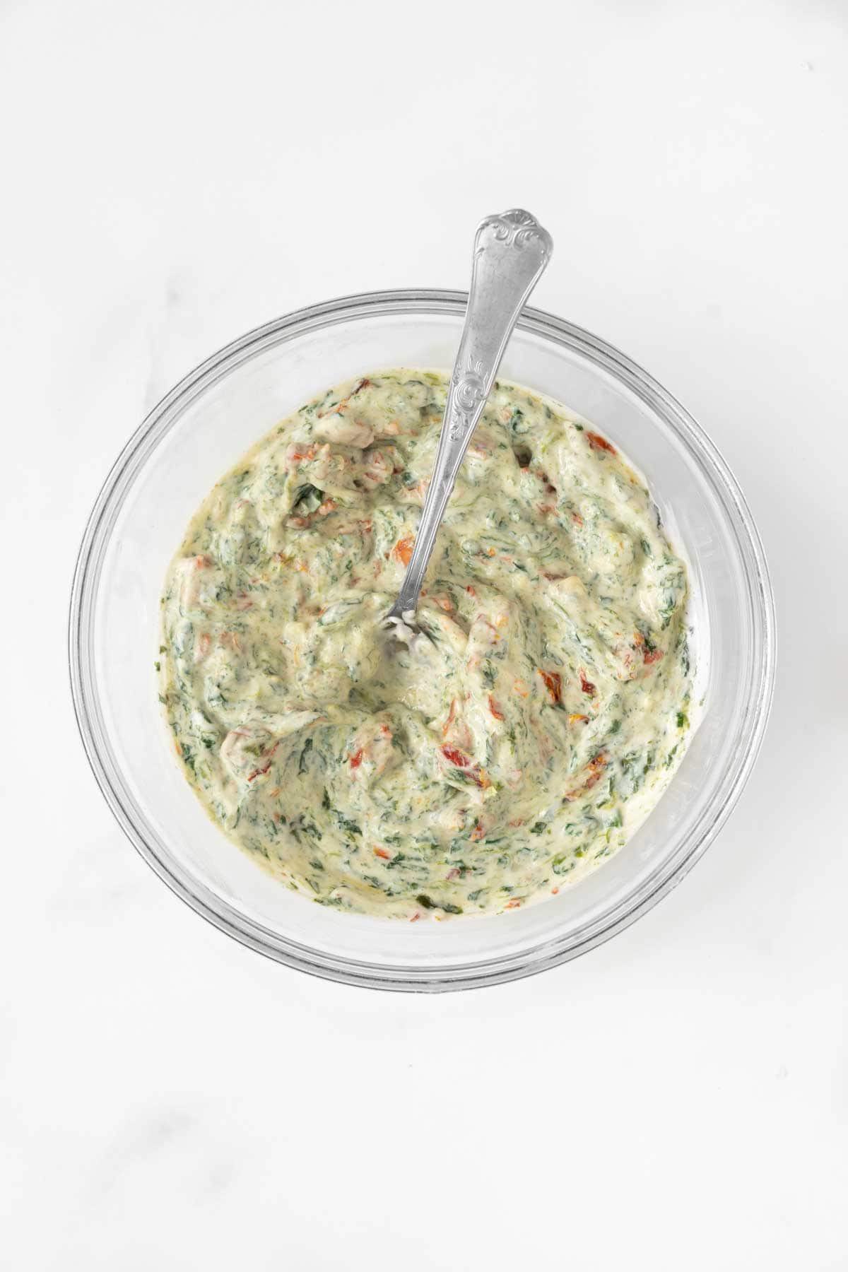 A cream cheese mix with herbs and vegetables in a bowl.