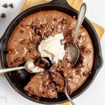 Skillet chocolate chip brownie topped with a scoop of vanilla ice cream.