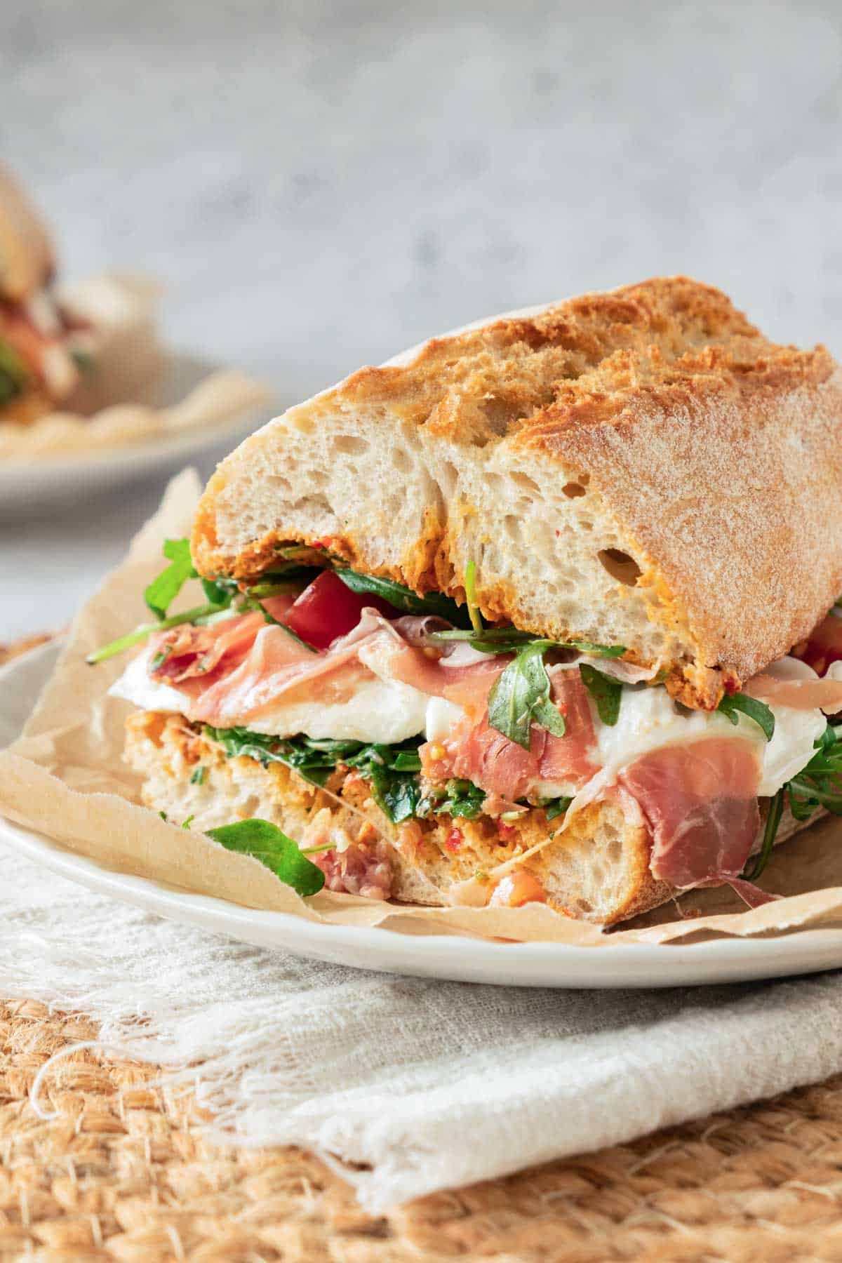 A fresh sandwich with prosciutto, arugula, and sun-dried tomatoes on ciabatta bread.