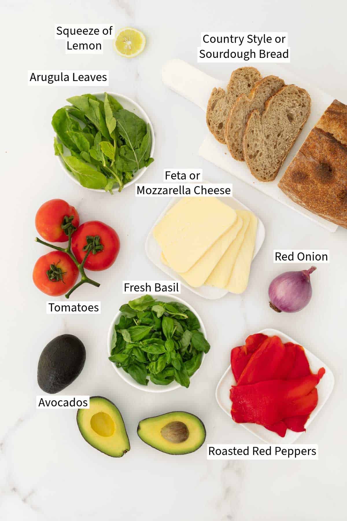 Ingredients for a Mediterranean Vegetable sandwich on a white table.