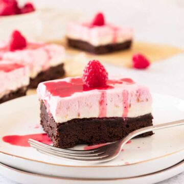 A square of Raspberry Cheesecake Brownie on a plate with a fork in front.