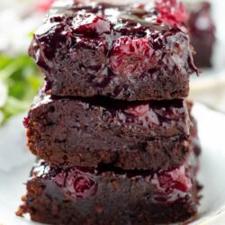 Chocolate cake with cherry topping stacked in three layers.