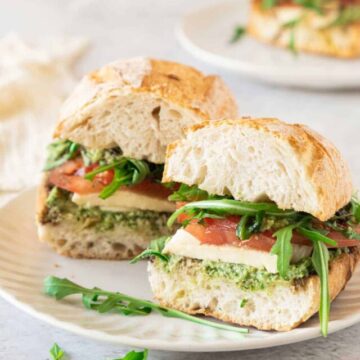 A sandwich with pesto and tomatoes on a plate.