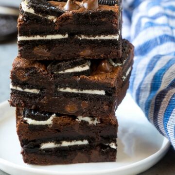 A stack of layered oreo brownies on a white plate with a striped napkin on the side.