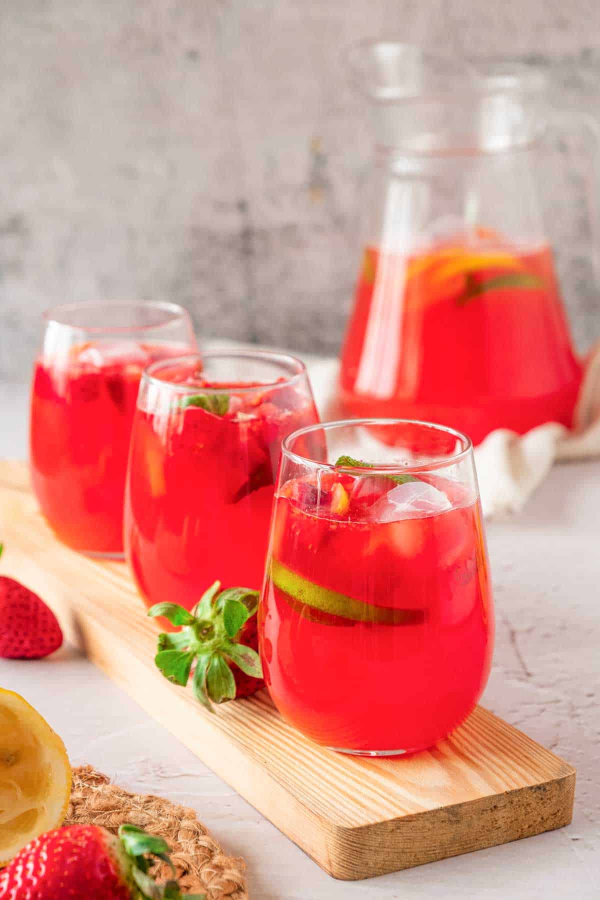 A pitcher and glasses of strawberry mint lemonade.
