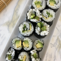 Plate of nori rolls with rice, avocado and cucumber.