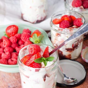 Jars of Eton Mess with cream and strawberries.