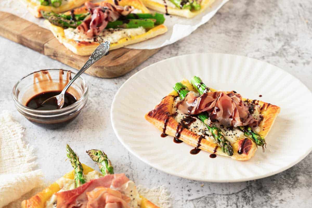 Puff pastry ricotta asparagus tartlets served with a side of balsamic glaze.