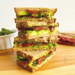 A stack of vegan sandwiches with sun-dried tomatoes and avocado.