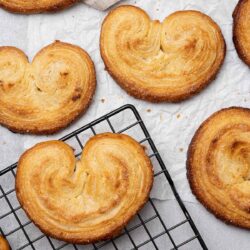 A close-up view of heart-shaped pastries arranged on a cooling rack and parchment paper.