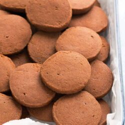 A tray filled with round, brown ginger snap cookies stacked on top of each other.