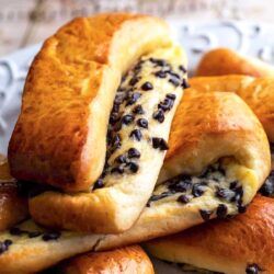 A close-up of several freshly baked bread rolls filled with chocolate chips, arranged on a plate.